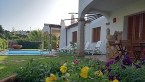 A pool area with lounge chairs and a stone wall. - Apartment I Gelsomini # (Tanaunella)