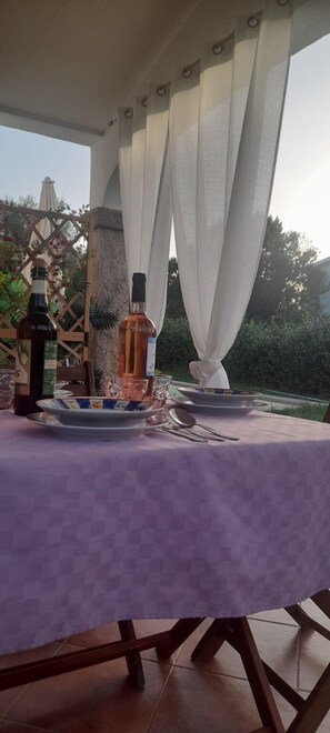 A table set for two with a purple tablecloth, two bottles of liquor, and a bowl of snacks. - Apartment I Gelsomini # (Tanaunella)