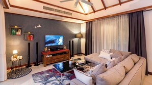 Una sala moderna con ventilador de techo, televisor de pantalla plana, sofá, mesa de centro y alfombra estampada.