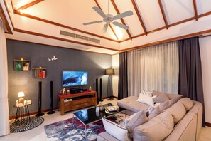 Una sala moderna con ventilador de techo, televisor de pantalla plana, sofá, mesa de centro y alfombra estampada.