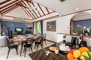 A modern living room with a dining area, a kitchen, and a seating area with a TV.
