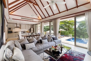 Un salon moderne doté d’un grand canapé, d’un coin repas et offrant une vue sur une piscine.
