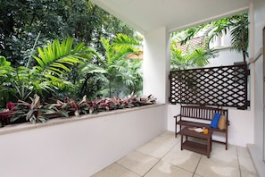 A balcony with a wooden bench, a small table, and a lattice partition.