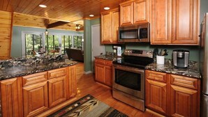 A kitchen with wooden cabinets, granite countertops, stainless steel appliances, and a view of the outdoors. - A River Runs Through It: Right on the River (Sevierville)