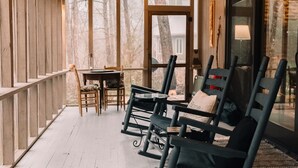A cozy porch with wooden railings, a table with chairs, and a bench with cushions. - A River Runs Through It: Right on the River (Sevierville)