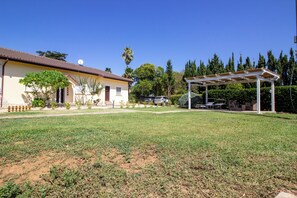 A house with a covered patio, a lawn, and a driveway with cars parked.
