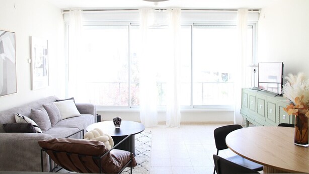 A bright living room with a sofa, a round table, and a cabinet. - MIKLAT Tranquil & Charming Apt near Hayarkon Park by FeelHome (Tel Aviv - Jaffa)