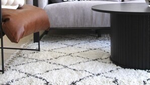 A modern living room with a grey sofa, a brown leather armchair, a black coffee table, and a patterned rug. - MIKLAT Tranquil & Charming Apt near Hayarkon Park by FeelHome (Tel Aviv - Jaffa)
