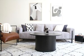 A modern living room with a sofa, a coffee table, and abstract art on the wall.