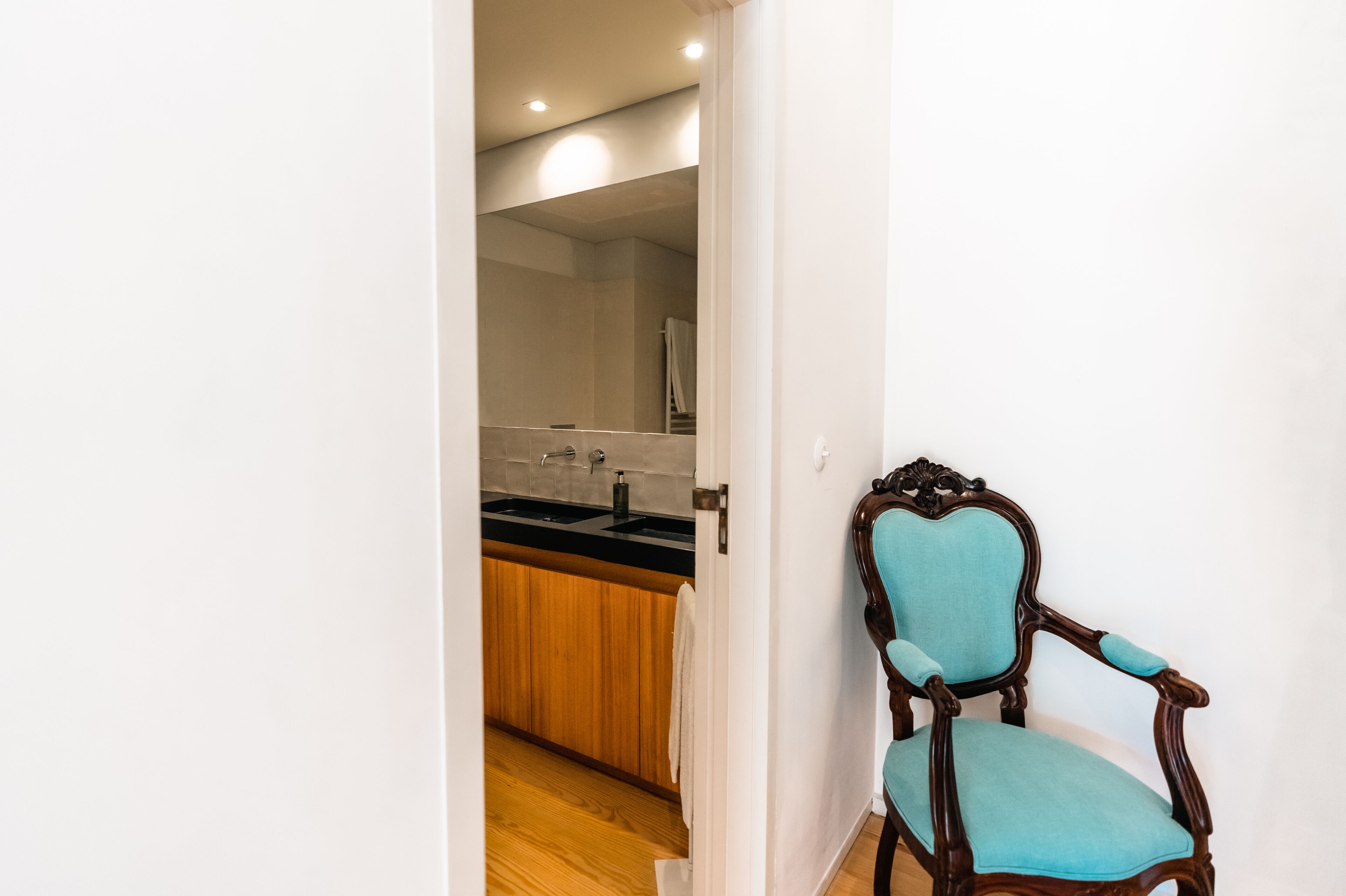 A hallway leading to a bathroom with a wooden cabinet and a sink.