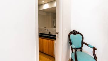 A hallway leading to a bathroom with a wooden cabinet and a sink.