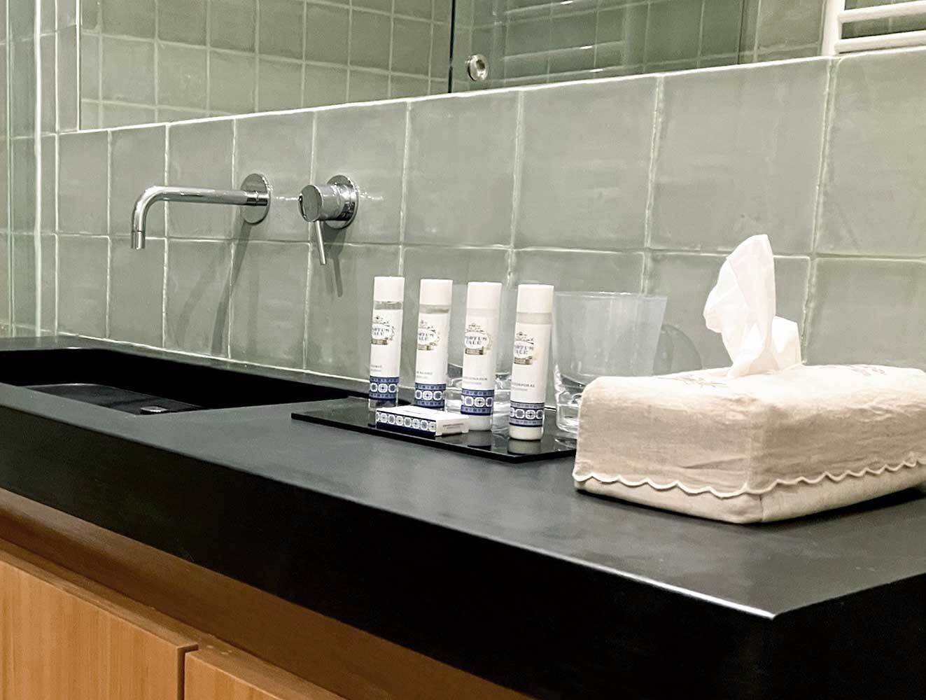 A bathroom sink with toiletries, a towel, and a mirror.