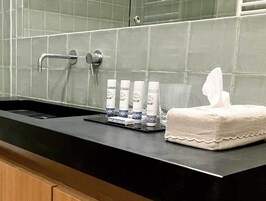 A bathroom sink with toiletries, a towel, and a mirror.