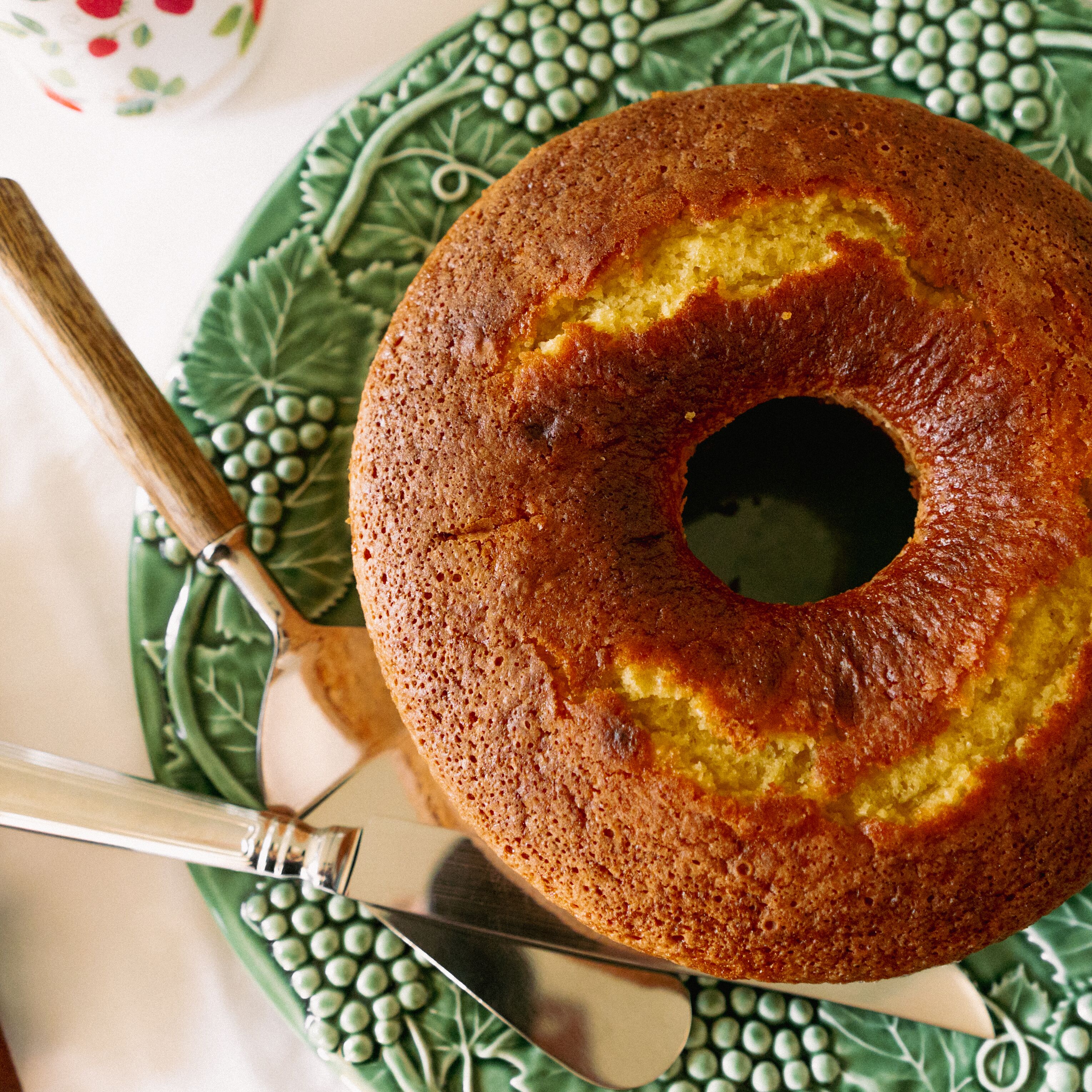 A bundt cake on a green plate with a knife.