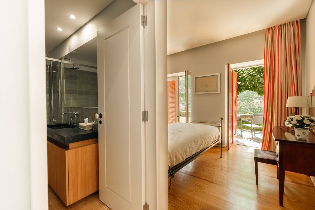 A modern bedroom with a bed, a desk, and a view of the outdoors.