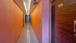 Un pasillo con suelo de mármol, paredes color naranja y una puerta de madera con un cartel que dice "1006".