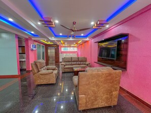 A modern living room with a sofa set, a coffee table, and a flat-screen TV mounted on the wall. - Hotel Grand Palace (Bengaluru)