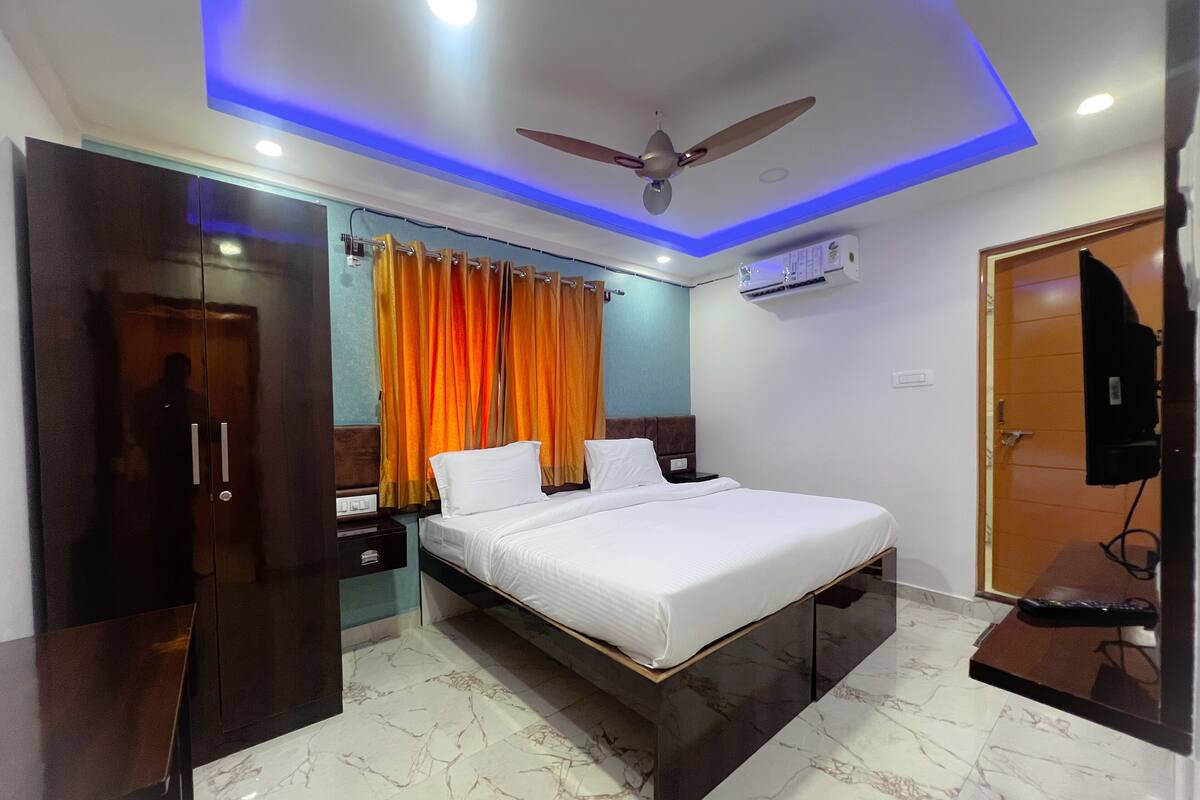 A modern bedroom with a bed, nightstands, a wardrobe, a ceiling fan, and an air conditioning unit.