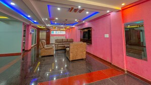 Un vestíbulo moderno con una pared roja, un ventilador de techo y una zona de estar con sofás y sillones.