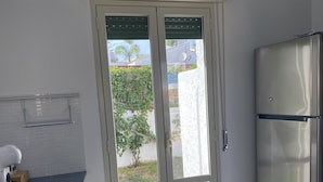 Eine moderne Küche mit einer Schiebetür aus Glas zum Garten, einem eingebauten Backofen und einem Edelstahl-Kühlschrank.