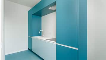 A modern kitchen with teal cabinetry, a white countertop, and a built-in sink.