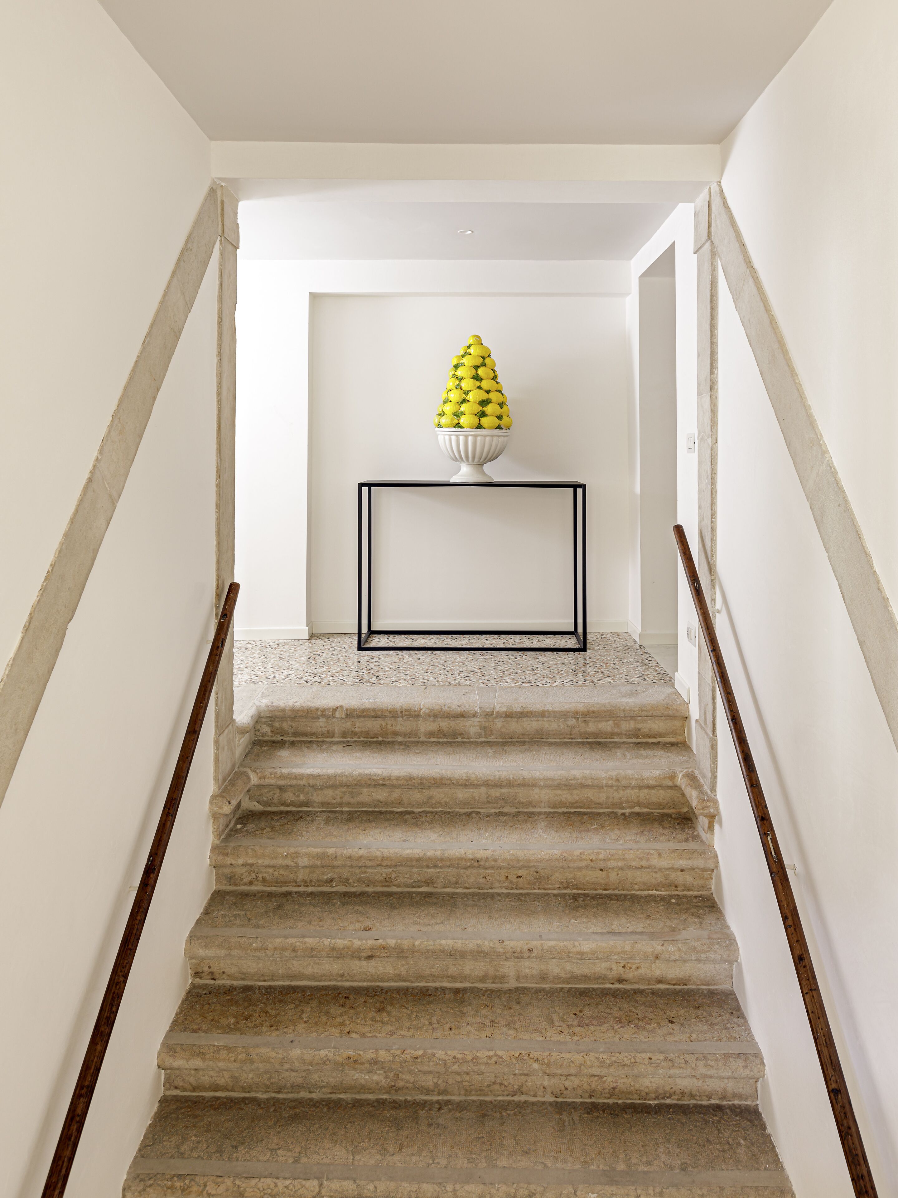 A staircase with a white wall and a framed artwork at the top.