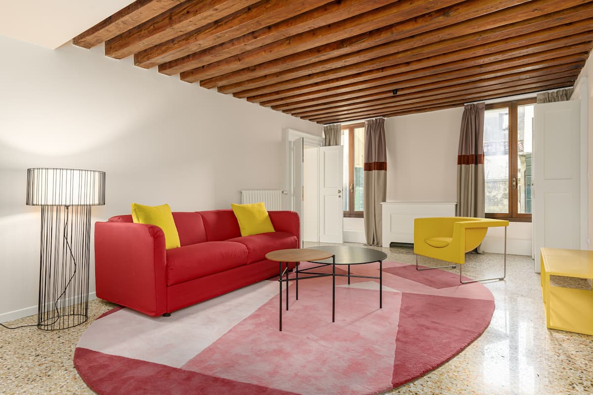 Una sala de estar moderna con un sofá rojo, un sillón amarillo y una pequeña mesa redonda.