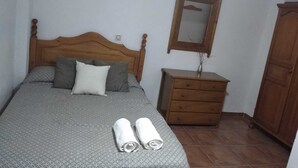 Un dormitorio con una cama de madera, una mesita de noche, un espejo y un armario.