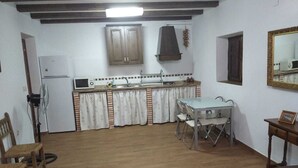 Una cocina compacta equipada con refrigerador, microondas, pileta y una mesa de comedor con sillas.