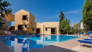 A swimming pool with lounge chairs and a building with multiple doors and windows. - Group Accommodation in Crete Separate Houses (Apokoronas)