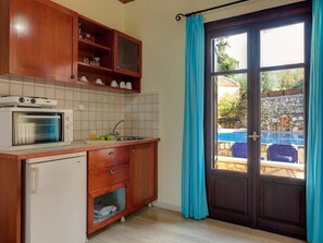 Una cucina con mobili in legno, forno a incasso e vista su una piscina attraverso una porta in vetro.