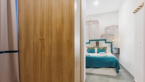 Habitación de hotel con un armario de madera, una cama con colcha color aguamarina y una pared con textura.