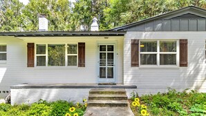 A white house with a front porch, a door, and windows with shutters.