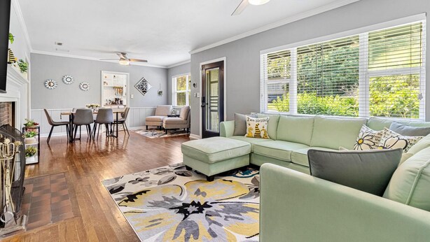 A modern living room with a sectional sofa, a dining area with a table and chairs, and a kitchen in the background.