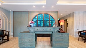 A room with a large, blue-toned desk with drawers, a decorative arch above it, and a traditional-style lamp. - Sino Siam Hotel (Krabi)