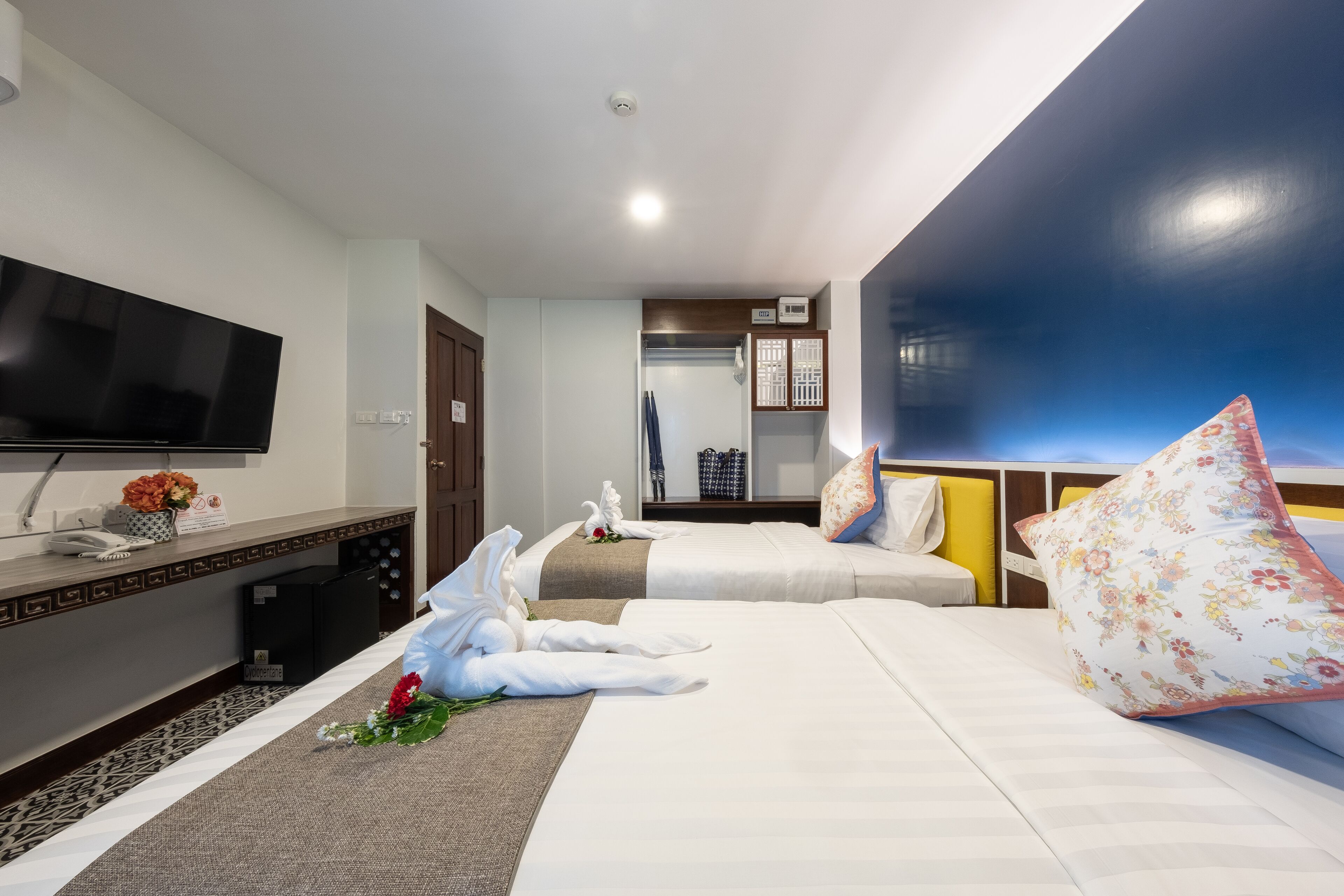 Une chambre d’hôtel avec deux lits, un téléviseur à écran plat, un bureau avec un téléphone et une armoire.