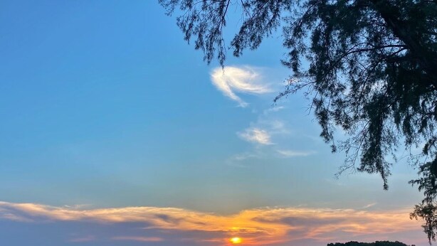 A beach with a sunset, calm sea, and distant mountains. - Sino Siam Hotel (Krabi)