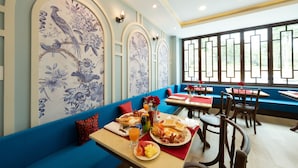 A restaurant with blue walls, floral murals, and a blue sofa. - Sino Siam Hotel (Krabi)