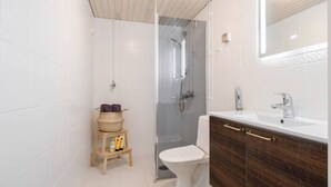 A modern bathroom with a glass-enclosed shower, a white toilet, and a wooden vanity with a mirror. - Design Apartment in the City Center and Garage (Hameenlinna)