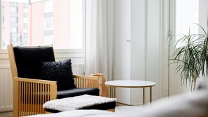 A modern living room with a wooden chair, a small round table, and a potted plant. - Design Apartment in the City Center and Garage (Hameenlinna)