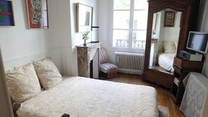 A bedroom with a large bed, a chair, a dresser, a television, and a window. - Appart aux Gobelins à 15 min à Pied de Saint Michel, Notre Damme et Montparnasse (Paris)