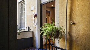 Un estrecho callejón con una reja de metal, una planta en maceta y la entrada de un edificio con una puerta de madera.