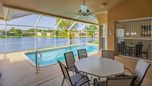 Un espace extérieur abrité comprenant une piscine, une table et des chaises.