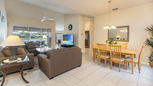Un salon spacieux comprenant un canapé, un téléviseur et un coin repas avec des chaises et une table.