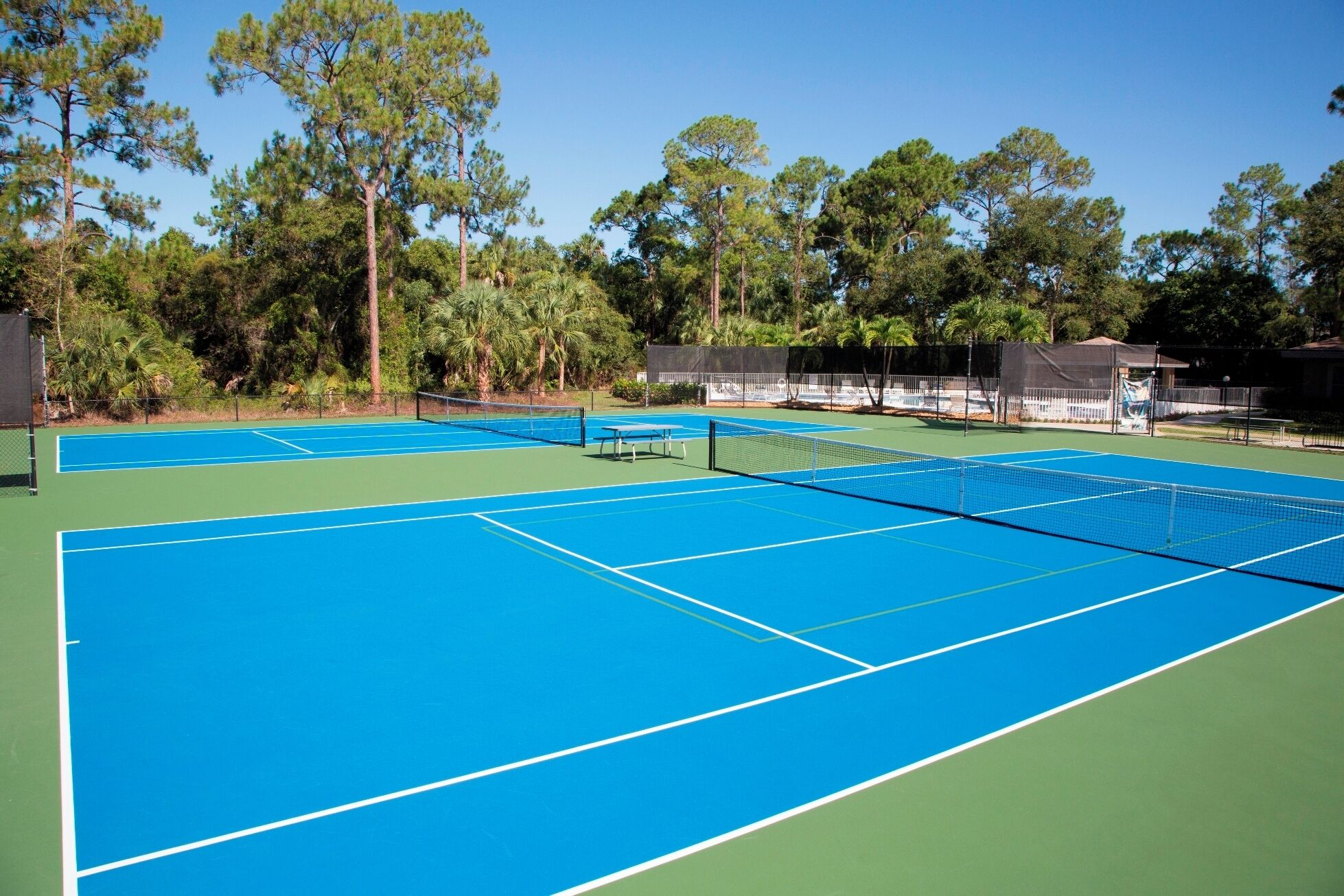 An outdoor tennis court with multiple courts and a net in the center.