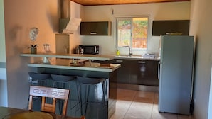 A compact kitchen with a central island, a refrigerator, and a window providing natural light.