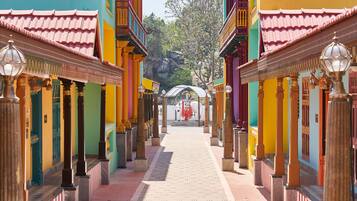 A pathway leading through colorful buildings with traditional architecture, including columns and lanterns.
