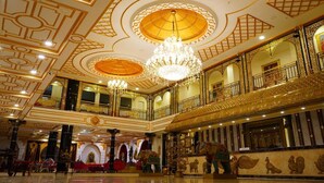 A grand hall with ornate ceiling designs, chandeliers, and a balcony with golden railings. - AR Thanga Kottai (Tirupattur)