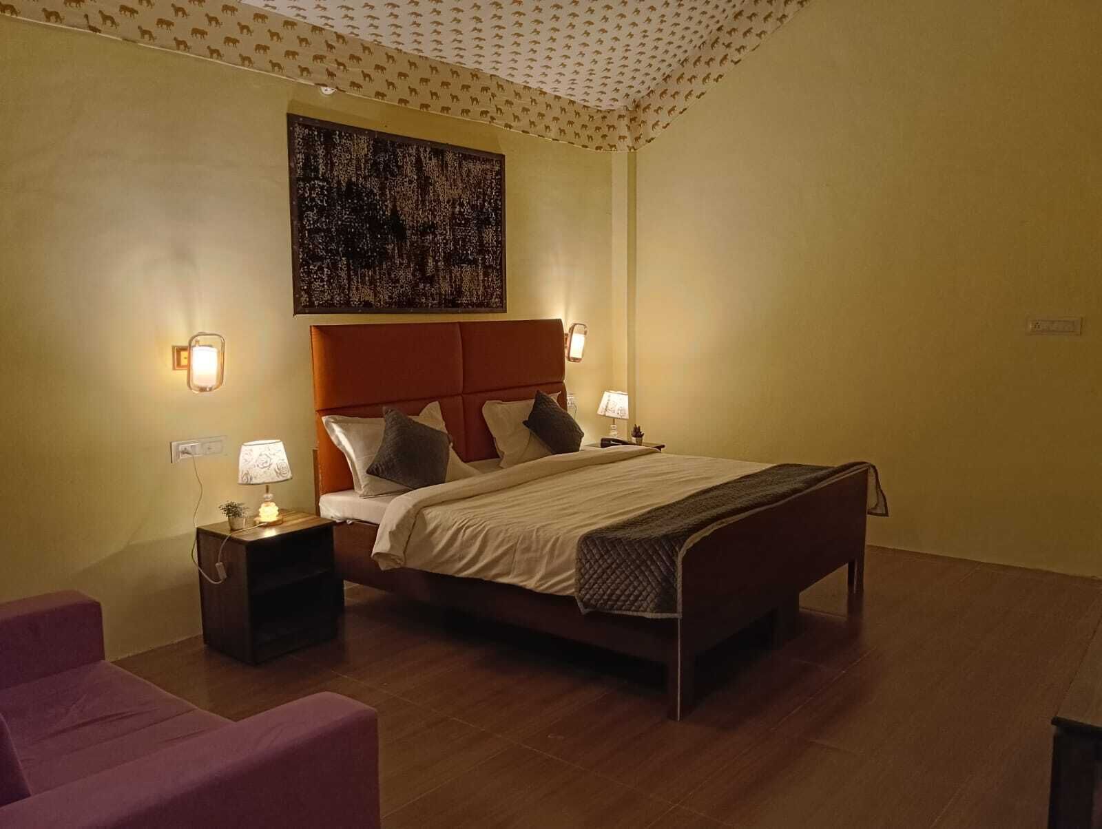 Habitación de hotel con cama, lámparas de noche, mesita de noche, una obra de arte en la pared y techo con diseño.