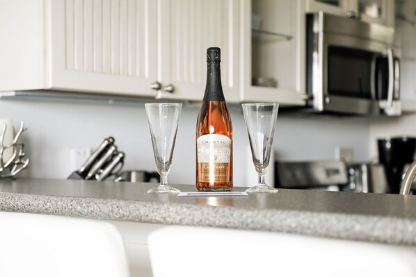 A bottle of champagne and two glasses on a kitchen counter. - The Shores Lake View Condo Unit 5574 (Williamsburg)